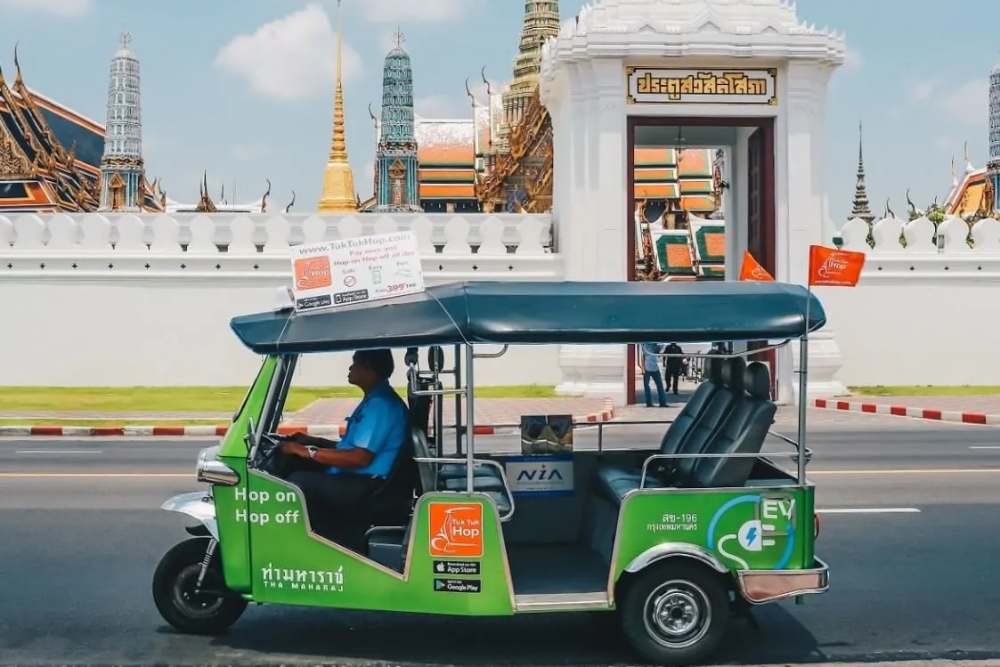 Un tuk tuk passe devant le palais royal thaïlandais.